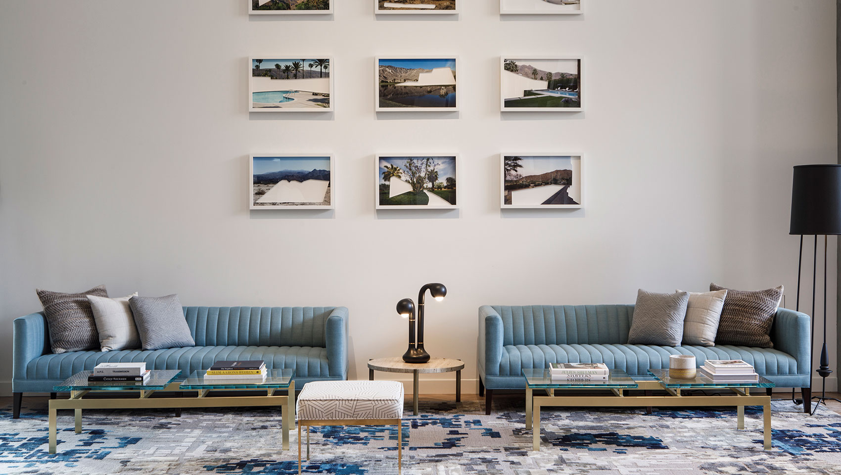 Rowan Lobby with blue couches, glass coffee tables, and framed photos on the wall
