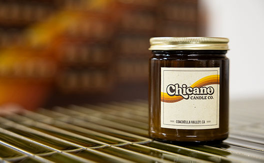 A brown and gold Chicano Candle Co. Candle